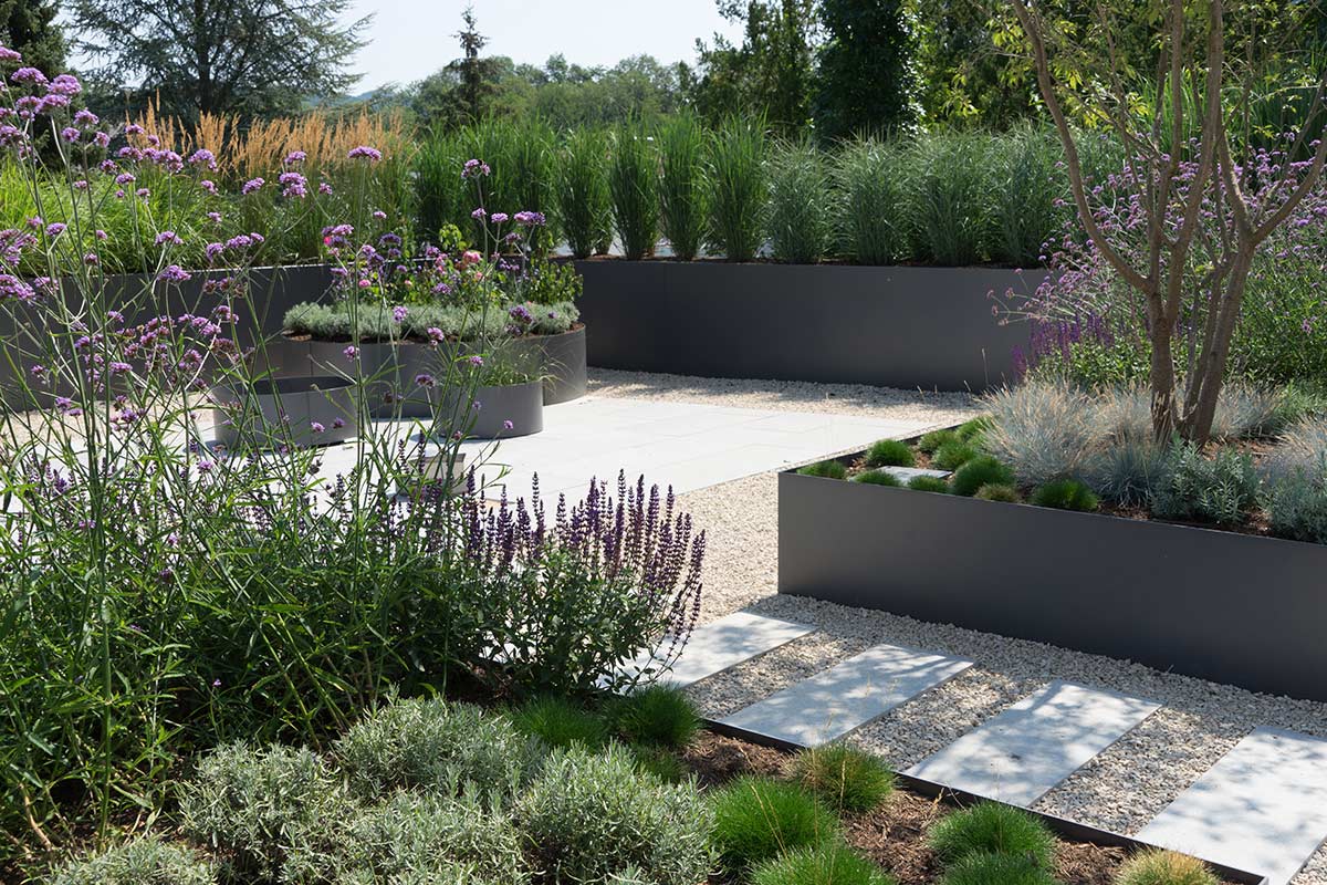 container garden with raised beds from aluminium in charcoal grey with a pathway and lots of green plants