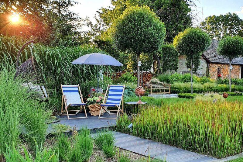large bespoke luxury family garden with a small decking area, rich planting and topiary trees.