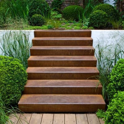 Corten steps in a garden against a contemporary white rendered retaining wall
