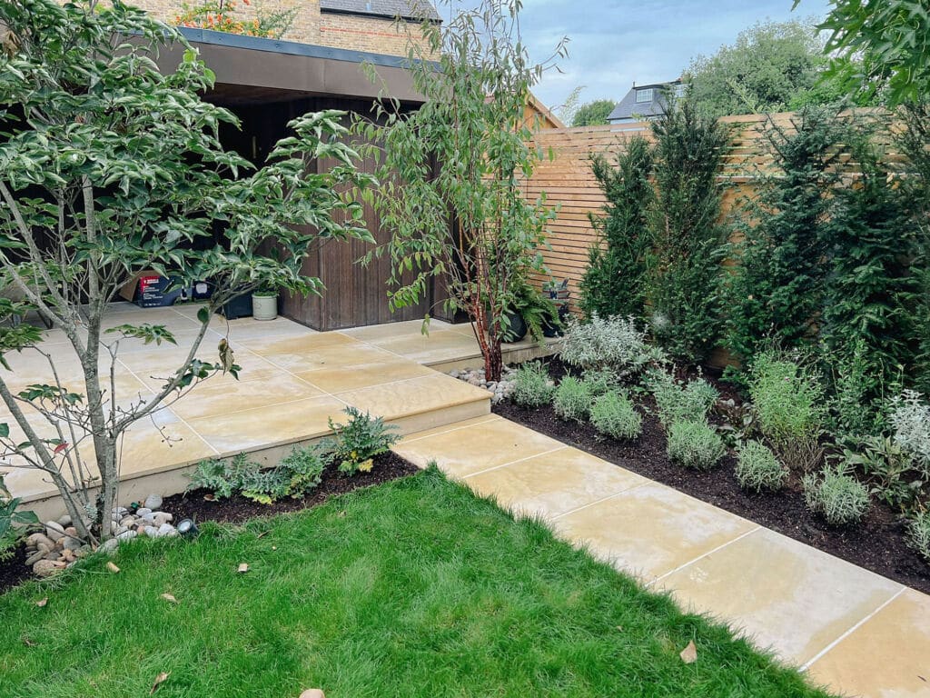 Contemporary garden with saw sandstone pathway, and garden room