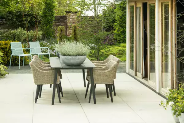 Contemporary garden patio outside a house with a table and chairs with an old wall in the background