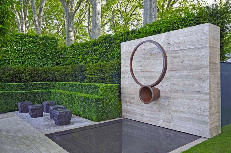 Modern garden design with a sleek concrete wall, reflecting pond, and contemporary planting