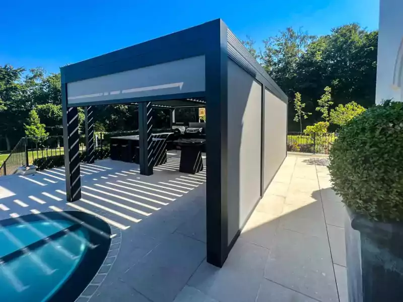 large aluminium pergola on a large patio with blinds and an outdoor kitchen