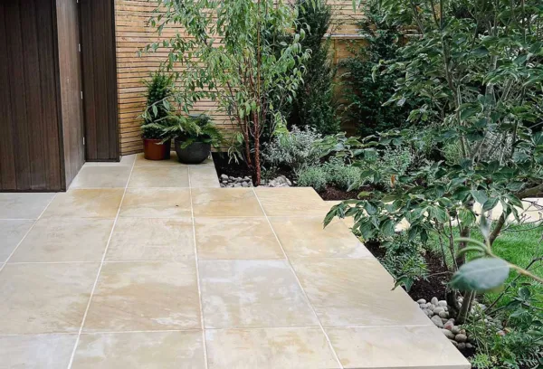 medium sized Contemporary garden with rich green planting, mature trees and sawn sandstone paving next to an outside office
