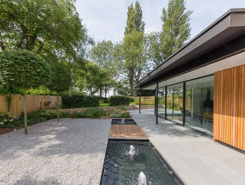 modern garden with gravel surface and a contemporary water feature in a large garden with topiary trees