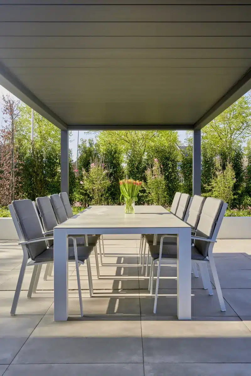 Mediterranean garden design with a aluminium pergola with the roof closed in a sunny garden giving the dining table and chairs lots of shade.
